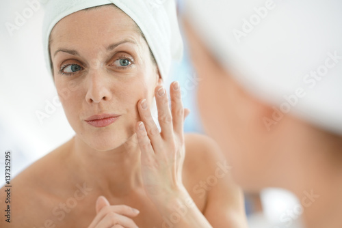 portrait of woman in bathroom applying moisturizing cream photo