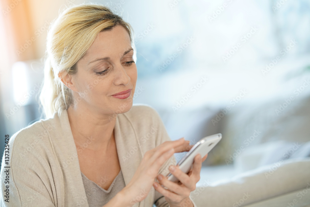 Blond woman sending text message with smartphone Blond woman sending text message with smartphone