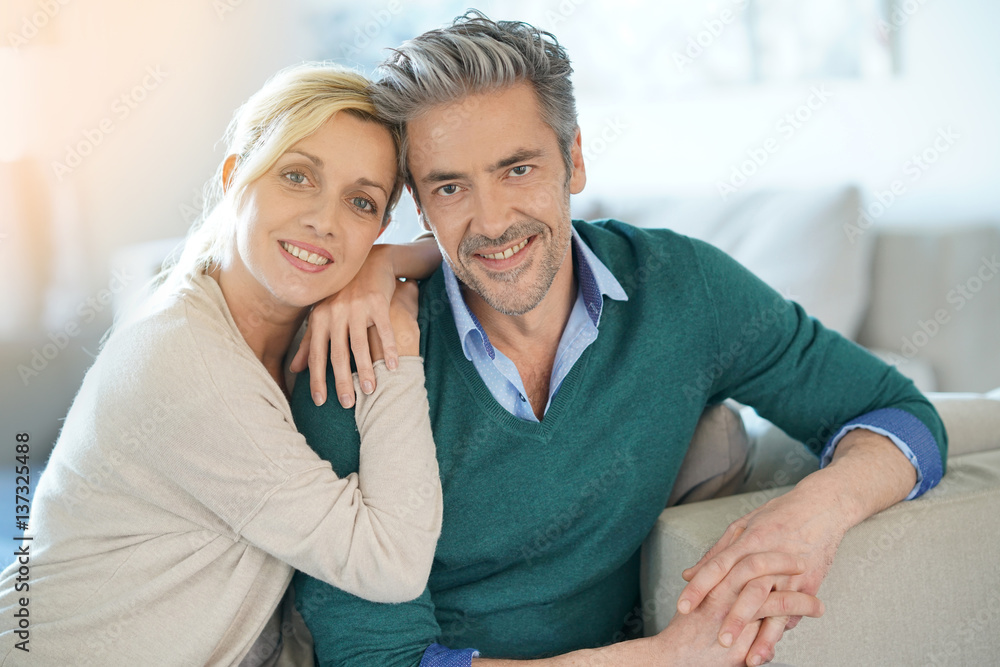 Portrait of middle-aged couple sitting in sofa at home Portrait of middle-aged couple sitting in sofa at home