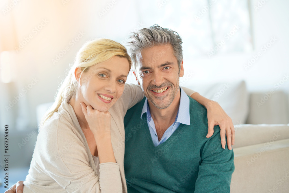 Portrait of middle-aged couple sitting in sofa at home Portrait of middle-aged couple sitting in sofa at home