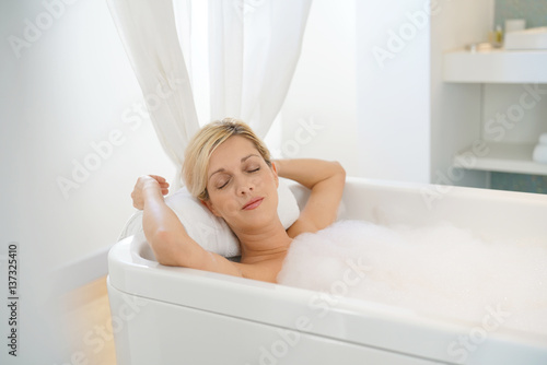 Beautiful blond woman relaxing in bathtub