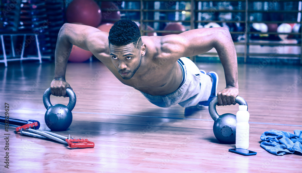 African american man doing push up workout in dark gym using kettlebell -  Black gritty face guy