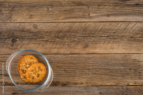 Peanut cookies in a glass bowl on old wooden table.