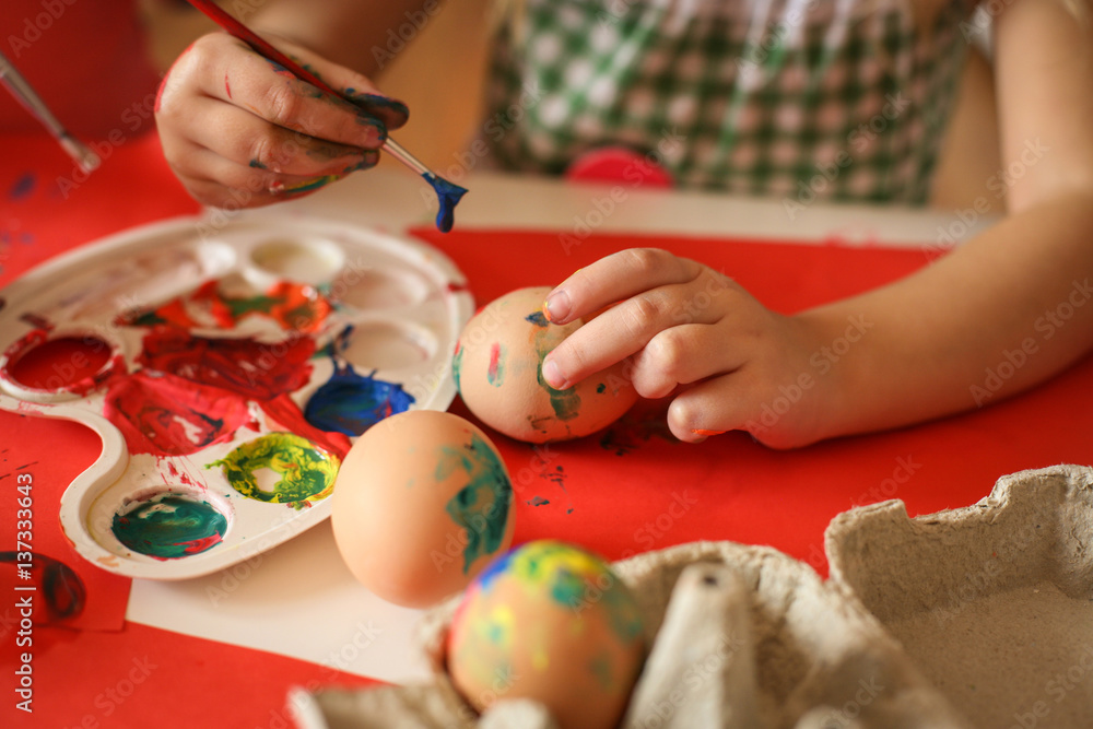Toddler having fun painting Easter eggs.
