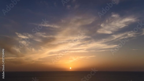 4k time lapse of clouds crossing the amazing sky over the sea or ocean at sunset. transition from day to night. The clouds cross slowly from left to right colored yellow orange purple blue