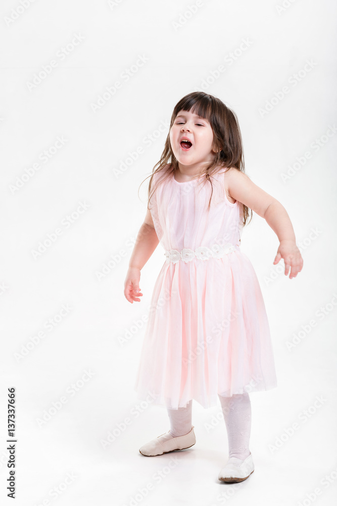 beautiful little girl in pink Princess dress naughty on a gray b