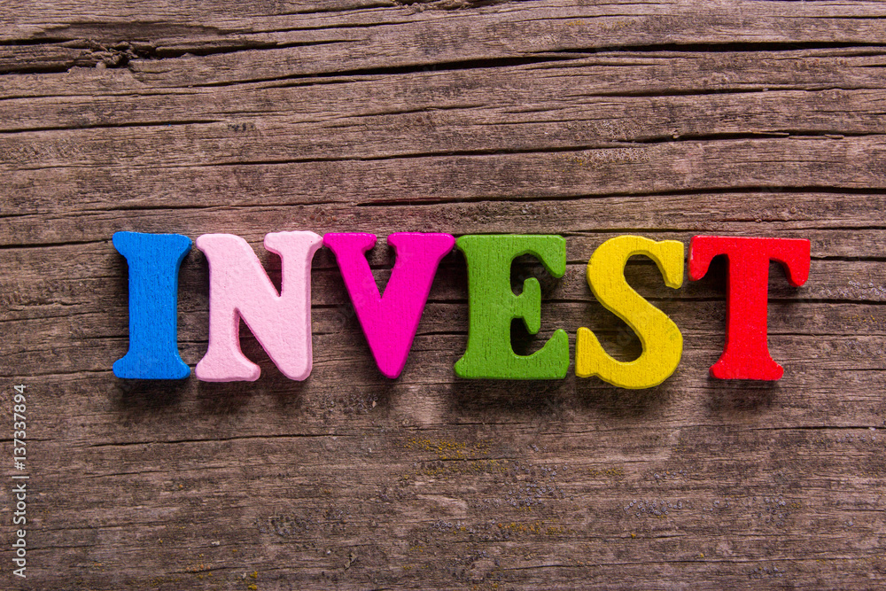 Fototapeta premium invest word made from colored wooden letters on an old table. Concept