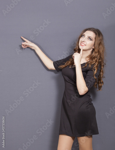  Attractive young girl in black dress holds finger up 