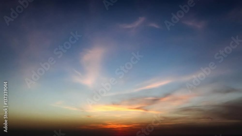 time lapse of clouds crossing the amazing sky over the sea or ocean at sunset. transition from day to night. The clouds cross slowly from left to right colored yellow orange purple blue