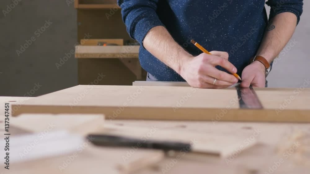 Young man working as carpenter and measuring board, dolly shot Young man working as carpenter and measuring board, dolly shot