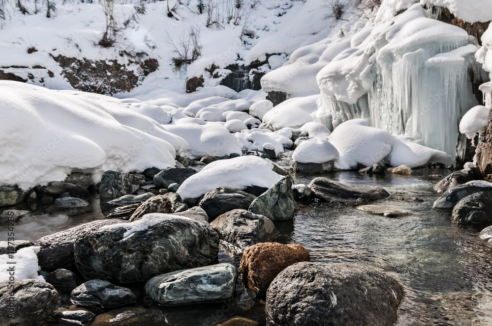 Fototapeta premium Winter landscape of mountain river with stones and small frozen waterfall