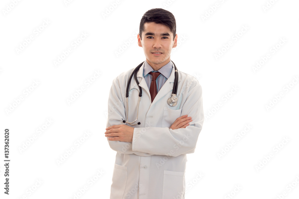 handsome young brunette man doctor in white uniform with stethoscope looking and smiling on camera isolated in studio handsome young brunette man doctor in white uniform with stethoscope looking and smiling on camera isolated in studio