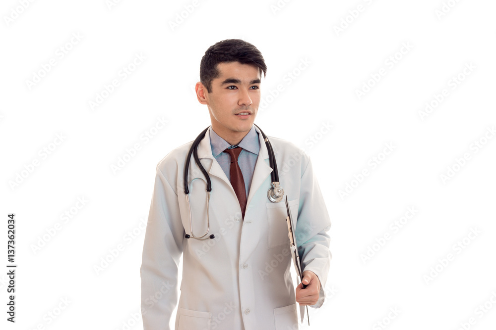 handsome young brunette man doctor in white uniform with stethoscope looking aside isolated in studio handsome young brunette man doctor in white uniform with stethoscope looking aside isolated in studio