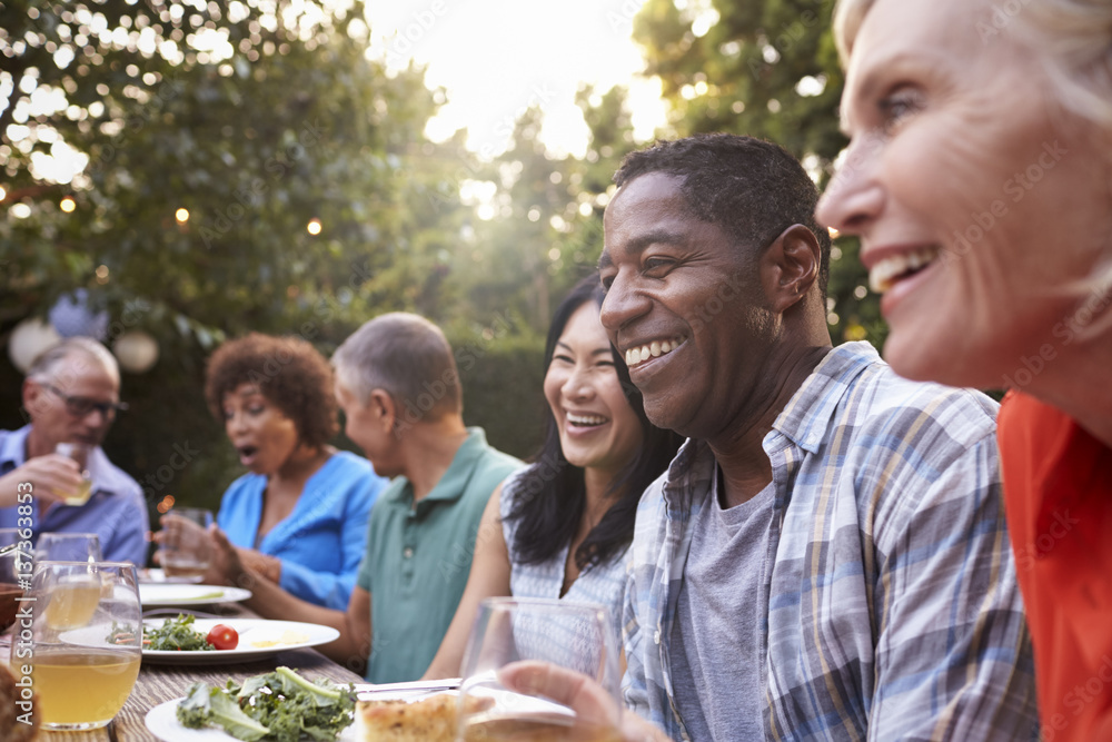 Group Of Mature Friends Enjoying Outdoor Meal In Backyard Group Of Mature Friends Enjoying Outdoor Meal In Backyard
