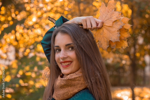 Portrait of a beautiful charming girl who keeps the leaves above her head and smiles at krupnyy plan photo