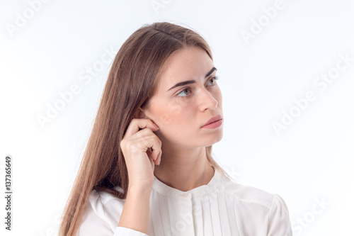 young girl looks away and keeps hand behind his ear is isolated on white background