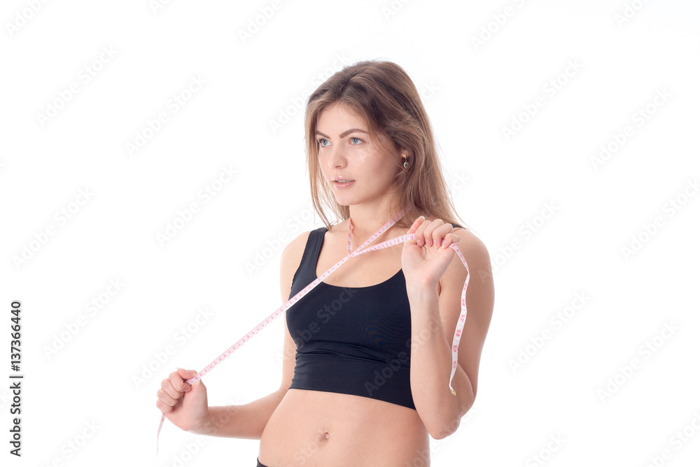 Pretty serious athletic girl who is standing sideways and holding a measuring tape Pretty serious athletic girl who is standing sideways and holding a measuring tape