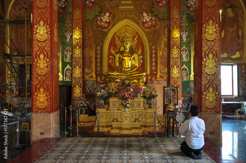 Praying man in front of a statue of Buddha in the temple