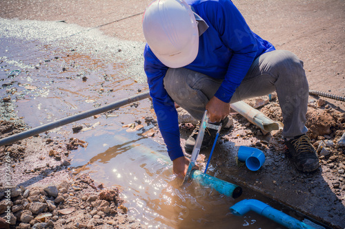 Construction worker,Repairing a broken water pipe on the concrete road.
