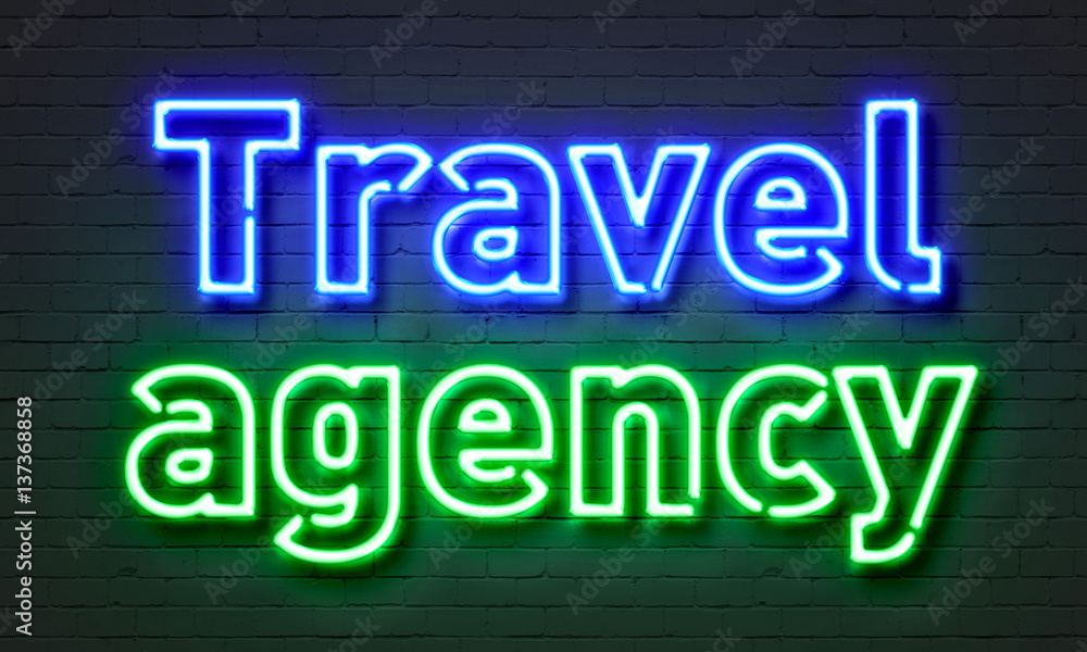 Travel agency neon sign on brick wall background.