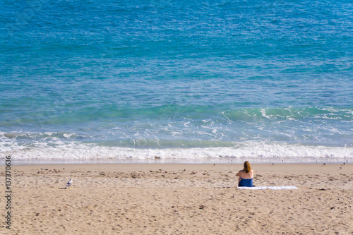 A woman sits on the beach in Stuart, Florida on a sunny Summer morning