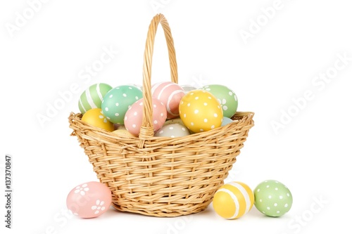 Easter basket filled with hand painted pastel Easter Eggs over a white background