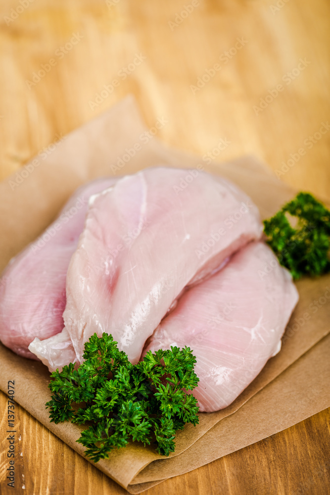 Raw chicken breasts and spices on wooden cutting board, close up view Raw chicken breasts and spices on wooden cutting board, close up view