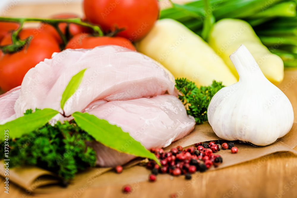 Raw chicken breasts and spices on wooden cutting board, close up view Raw chicken breasts and spices on wooden cutting board, close up view