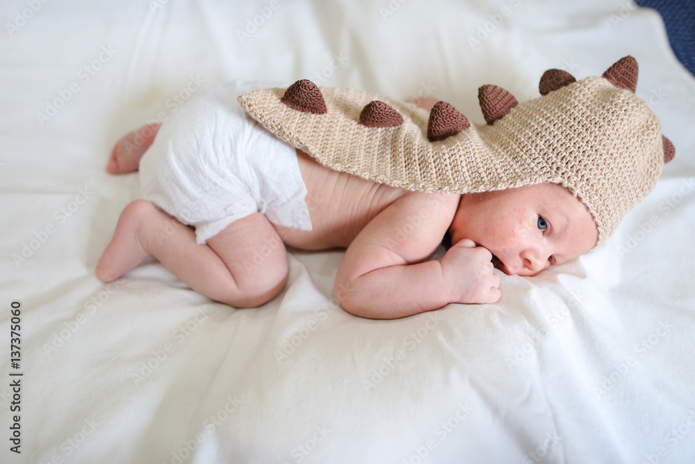 Newborn baby lying on bed and dressed in funny baby clothes in b Stock  Photo | Adobe Stock