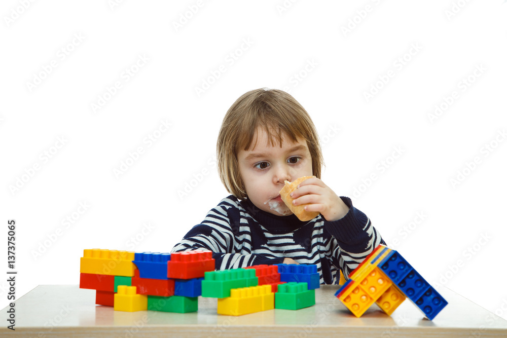 Serious little girl playing in the constructor and eating ice cream. Shooting on a white background. Serious little girl playing in the constructor and eating ice cream. Shooting on a white background.