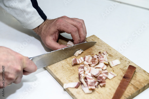 Thin cut bacon on a wooden board with a knife
