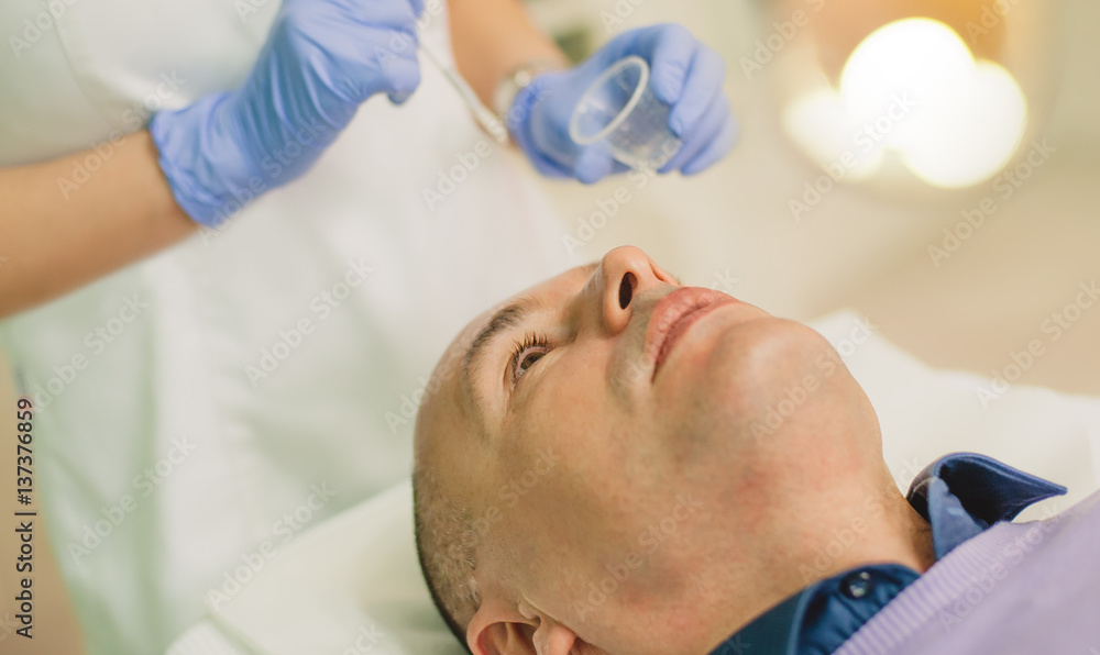 Relaxed man having a face massage and a peeling treatment Relaxed man having a face massage and a peeling treatment