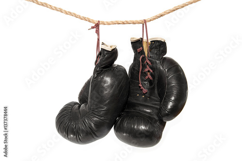 Old boxing gloves hanging on a rope on a white background