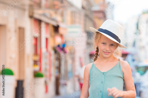 Adorable happy little girl outdoors in european city. Portrait of caucasian kid enjoy summer vacation in Europe