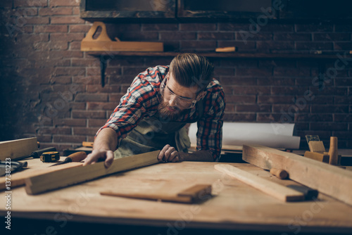фотографія Bearded handsome cabinetmaker at the tabletop with tools