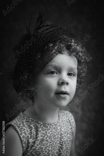 Portrait of cute little girl with hat on her head. Positive expression of shy child.