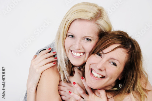 Portrait of two young women hugging each other. Isolated with light background. photo