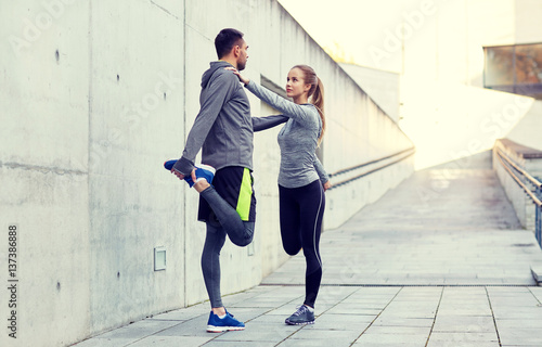 smiling couple stretching leg outdoors