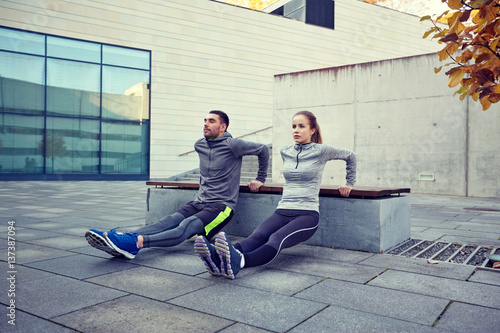 Fototapeta Naklejka Na Ścianę i Meble -  couple doing triceps dip exercise outdoors