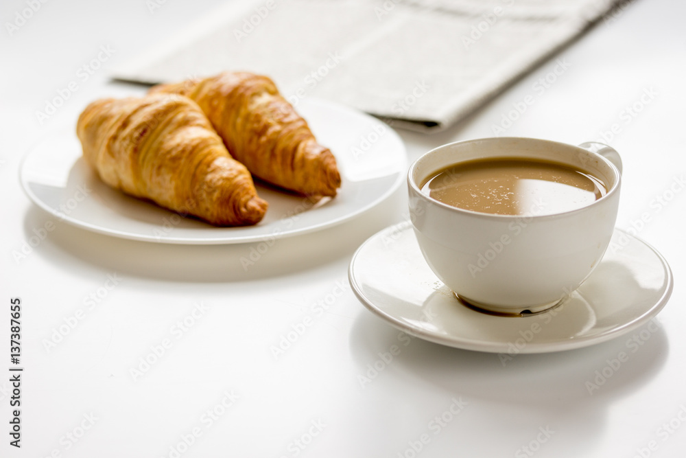 Breakfast for businessman with coffee and croissant on white table Breakfast for businessman with coffee and croissant on white table