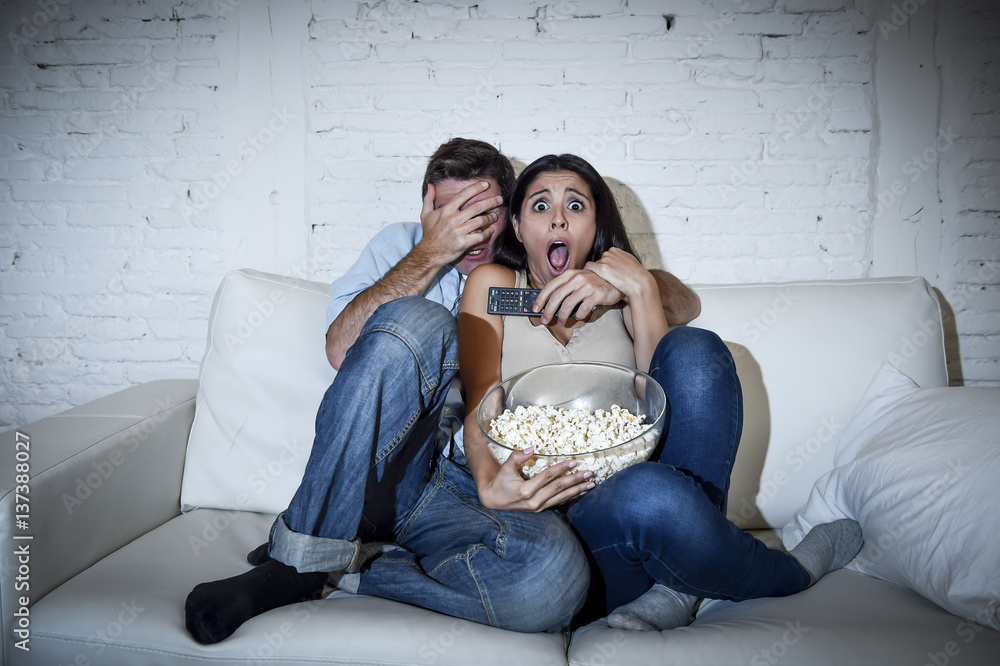 Naklejka premium attractive couple having fun at home enjoying watching television horror movie show