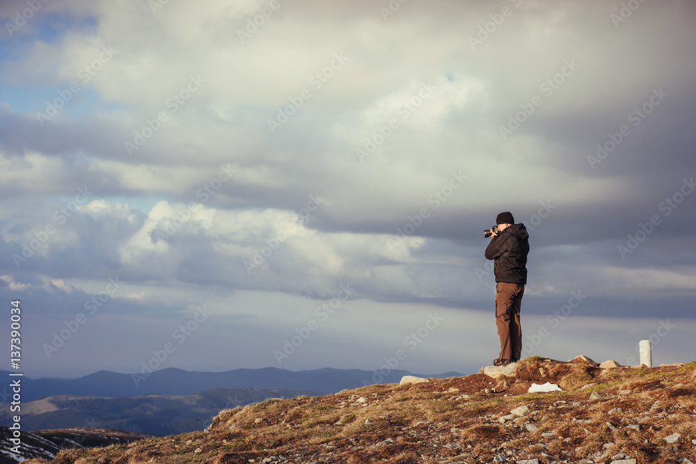 tourist looks at the landscape. Photographer on top of mountain