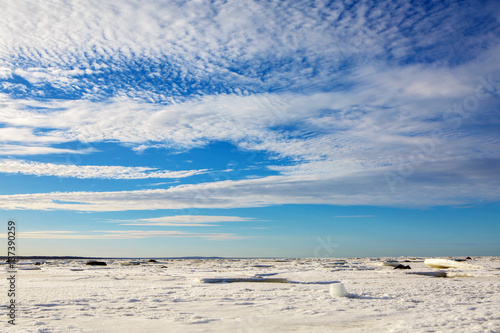 Beautiful panorama of the North sea frozen in the ice. Nature water icy in the winter. Landscape snowy expanse to the horizon with a wonderful sky and clouds.