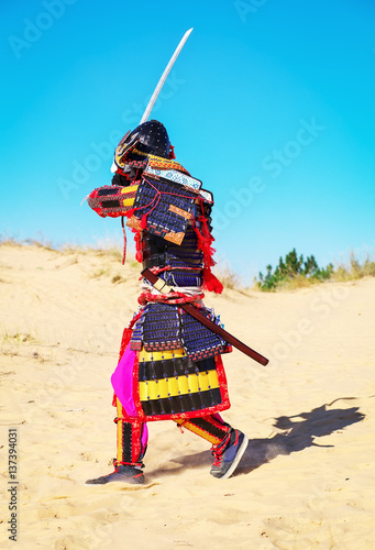Men in samurai armour with sword running on sand