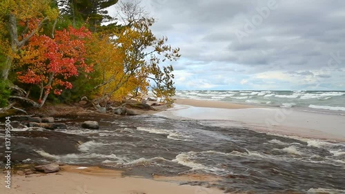 The Hurricane River flows out from woods with fall colors and across the beach and into Lake Superior at Pictured Rocks National Lakeshore in the Upper Peninsula of Michigan. photo