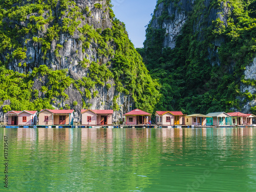 Tableau sur toile Floating fishing village reflected in emerald waters of Ha Long bay, Vietnam
