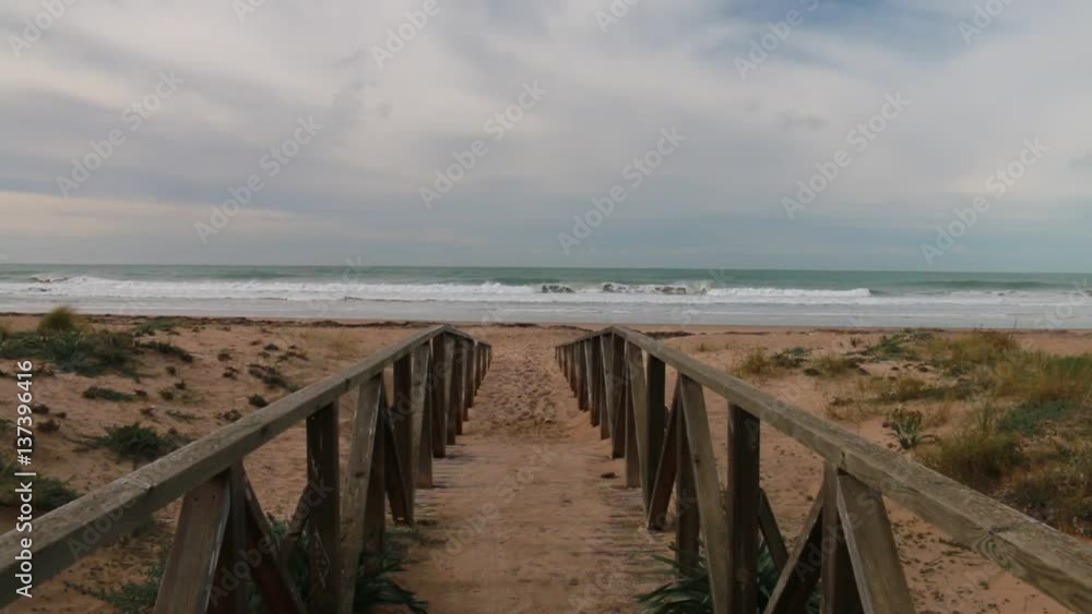 Wooden path to the beach and the background sea waves