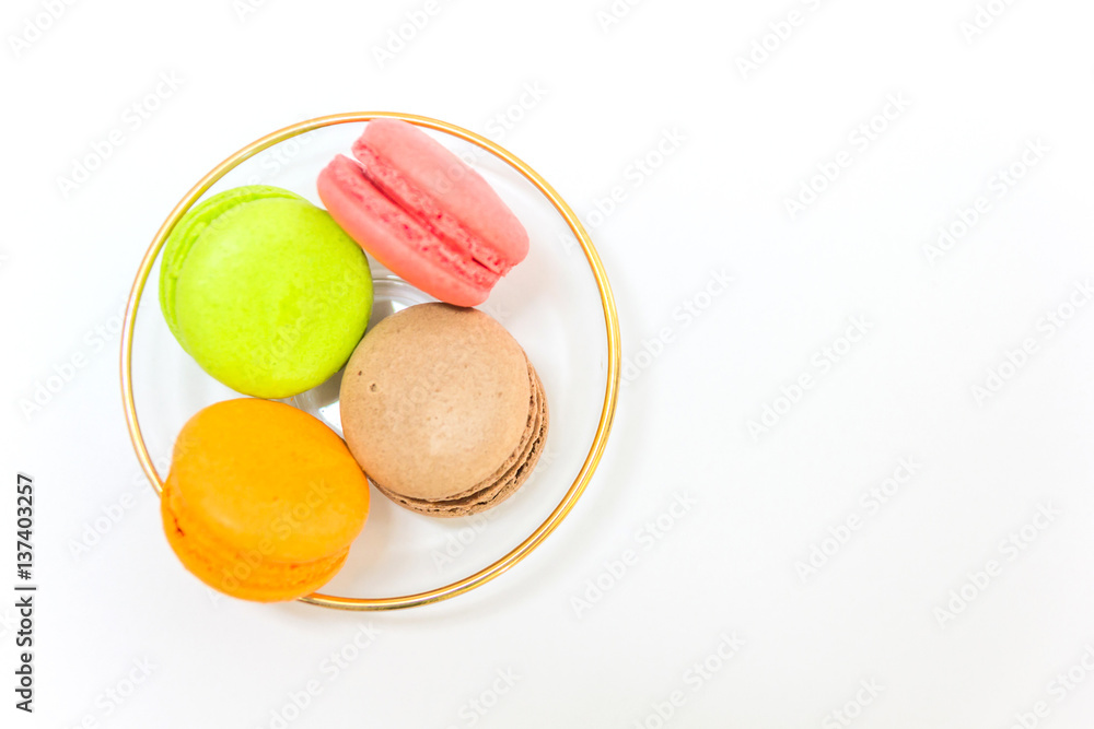 Sweet and colourful french macaroons or macaron in a glass bowl on white background, Top view with copy space for your text. Sweet and colourful french macaroons or macaron in a glass bowl on white background, Top view with copy space for your text.