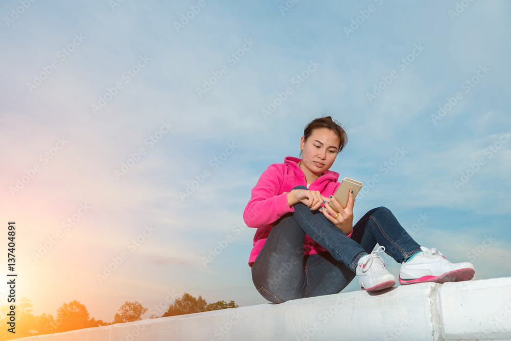 young woman using a smart phone at sunset.