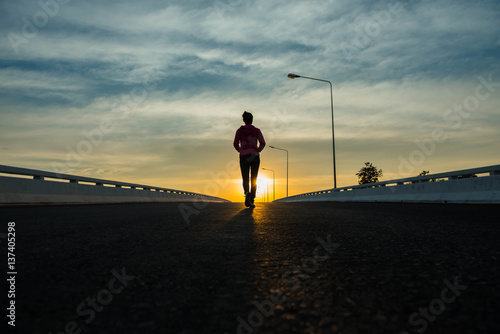 silhouette woman walking on the street at sunset. © stcom